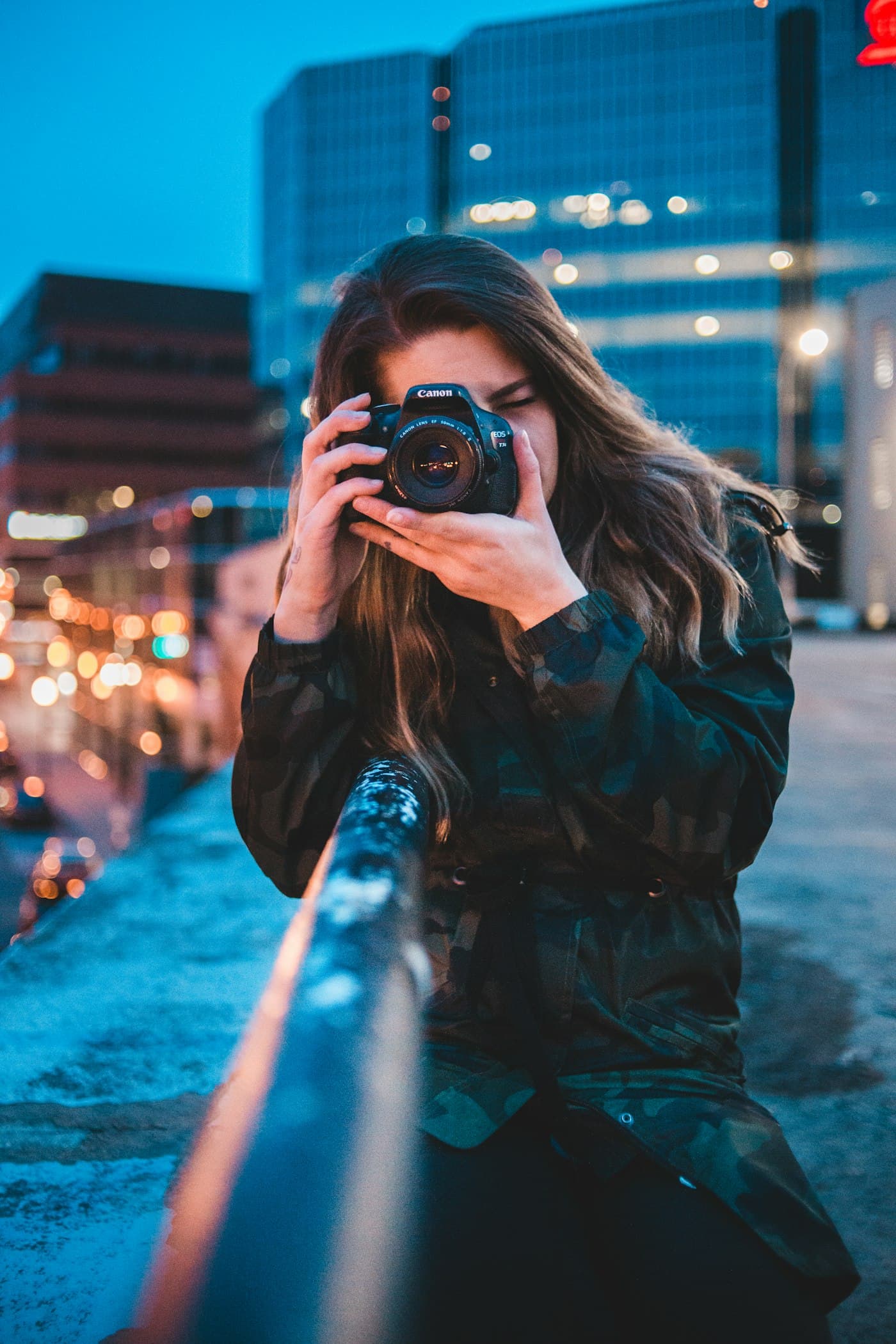 A creator holding a camera to her eye against night-time city lights
