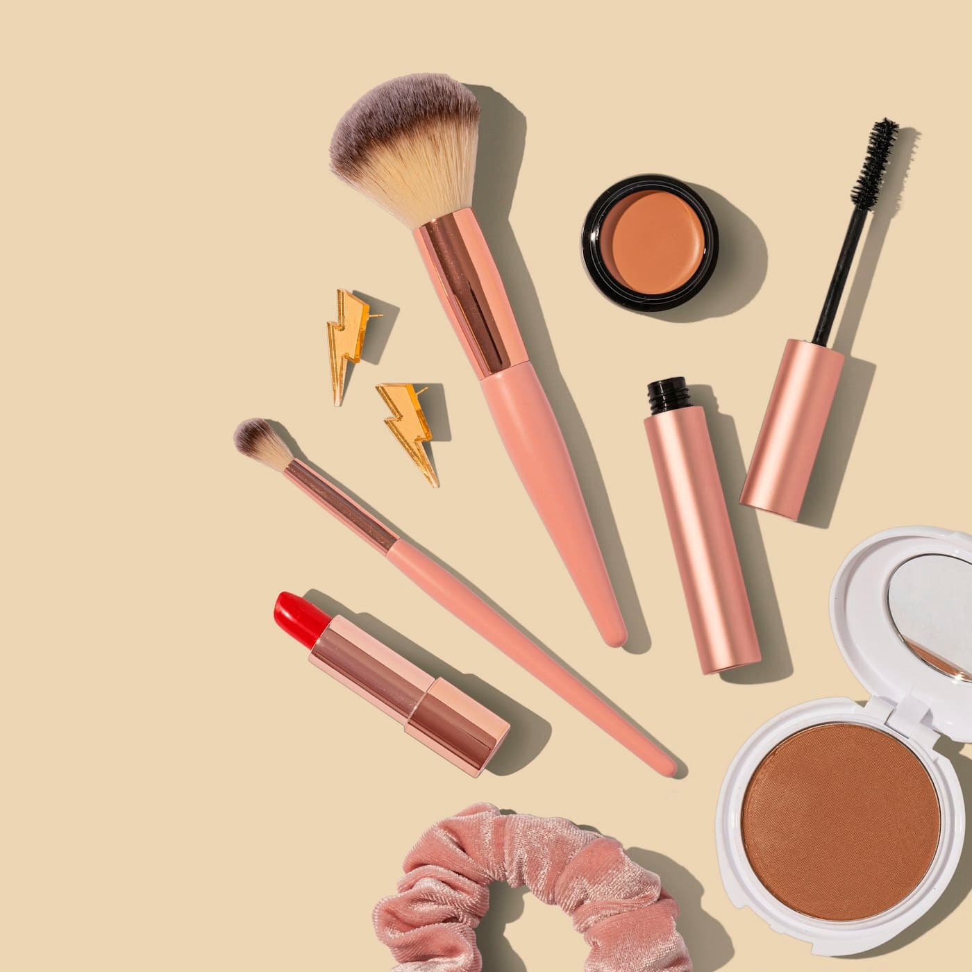 Cosmetics and brushes arranged on a warm beige background