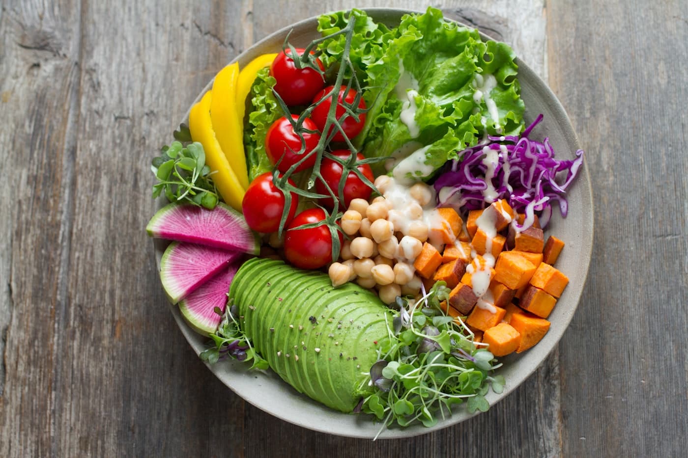 A bright vegetable bowl photographed from above on a wooden table