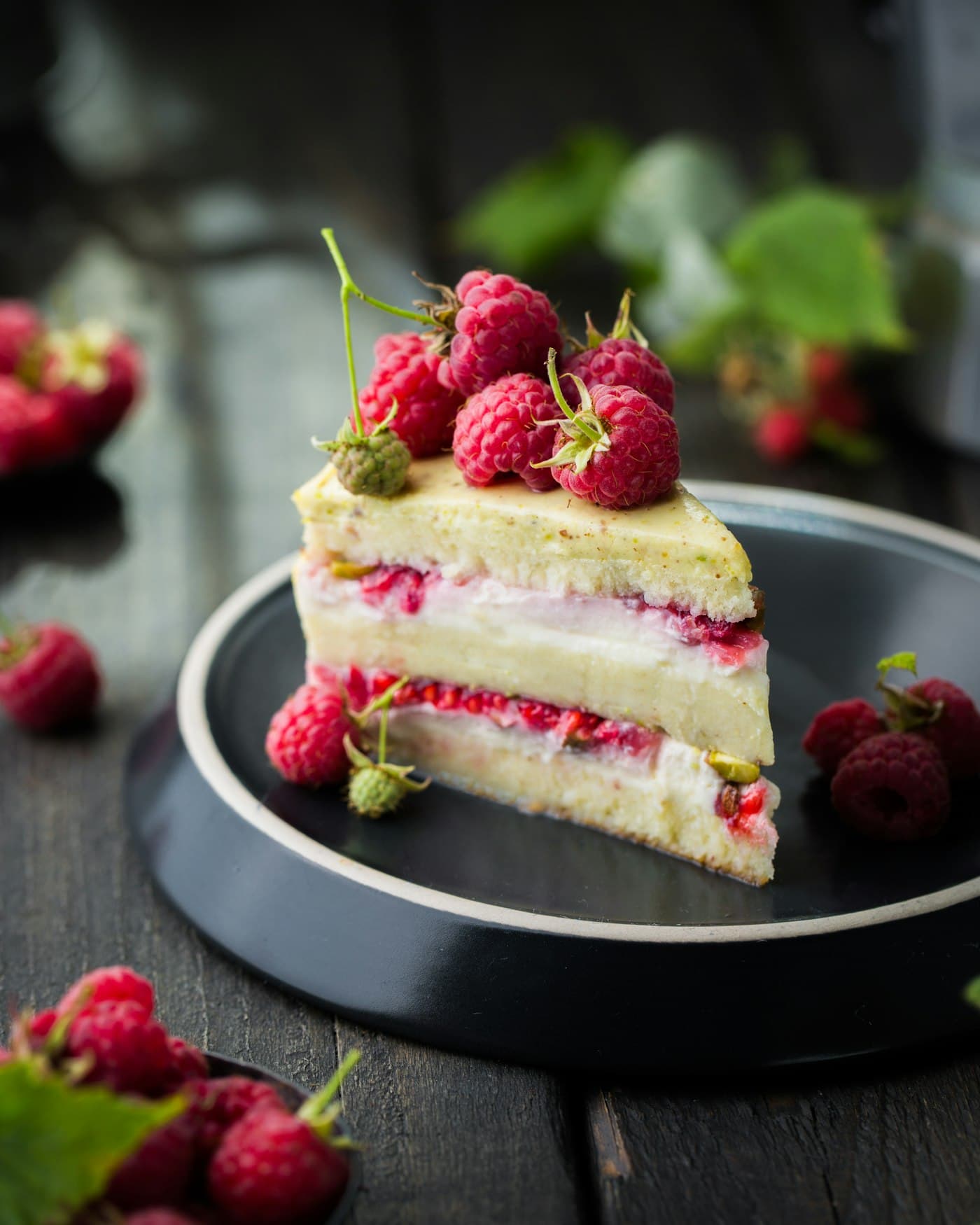A slice of layered raspberry cake on a dark plate