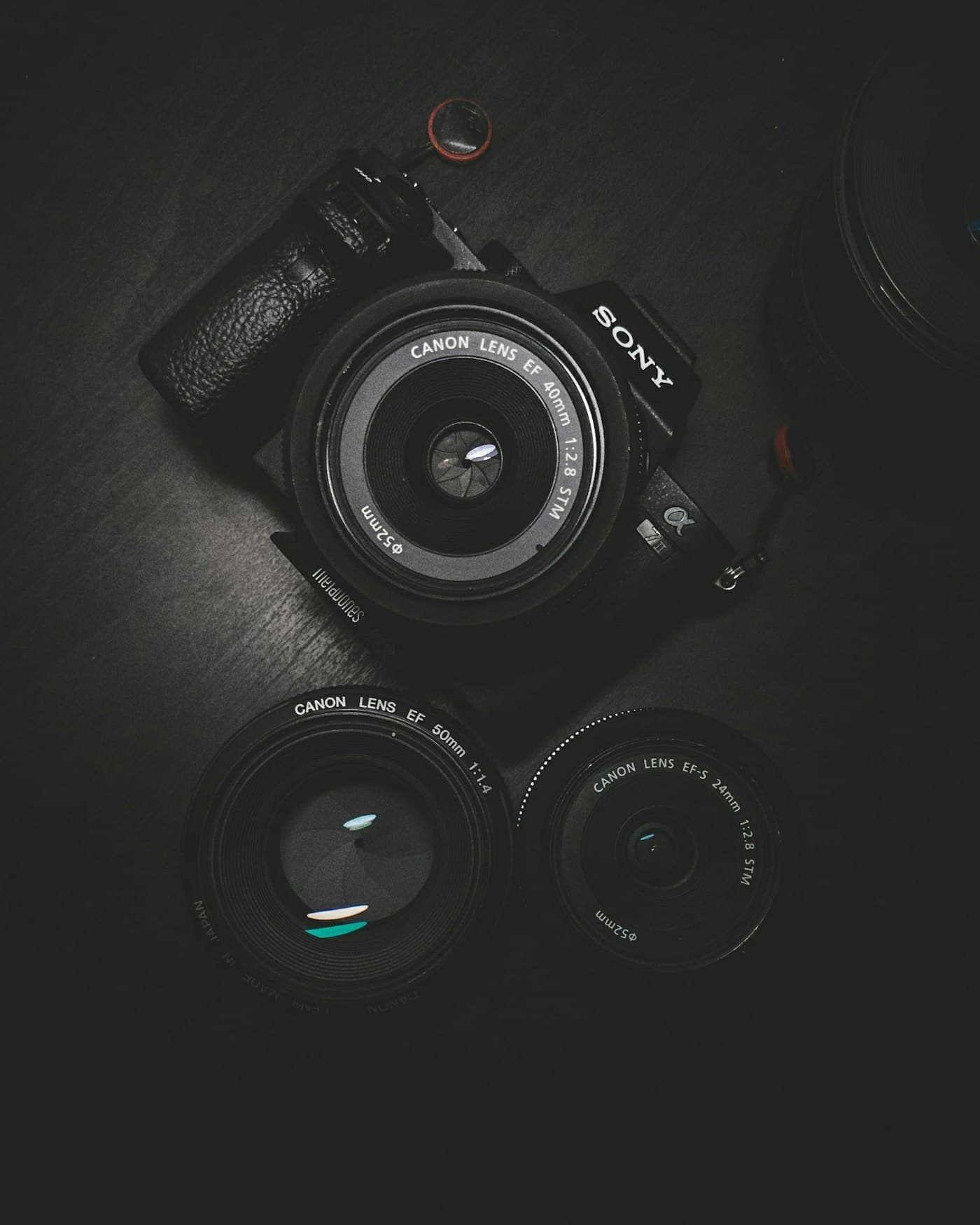 Camera lenses laid out on a black surface, catching a low light